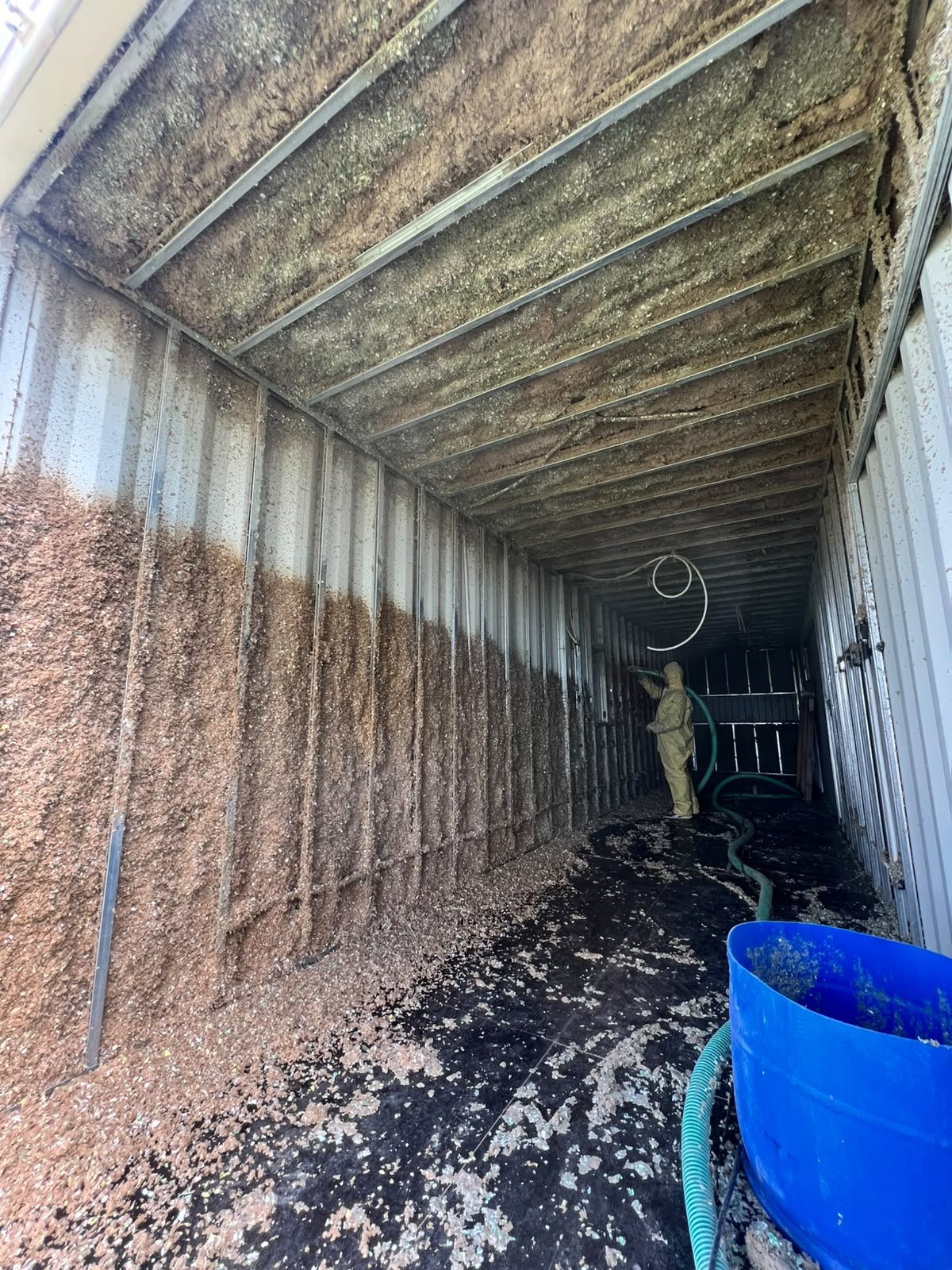 Operario proyectando celulosa sobre techo y paredes del container